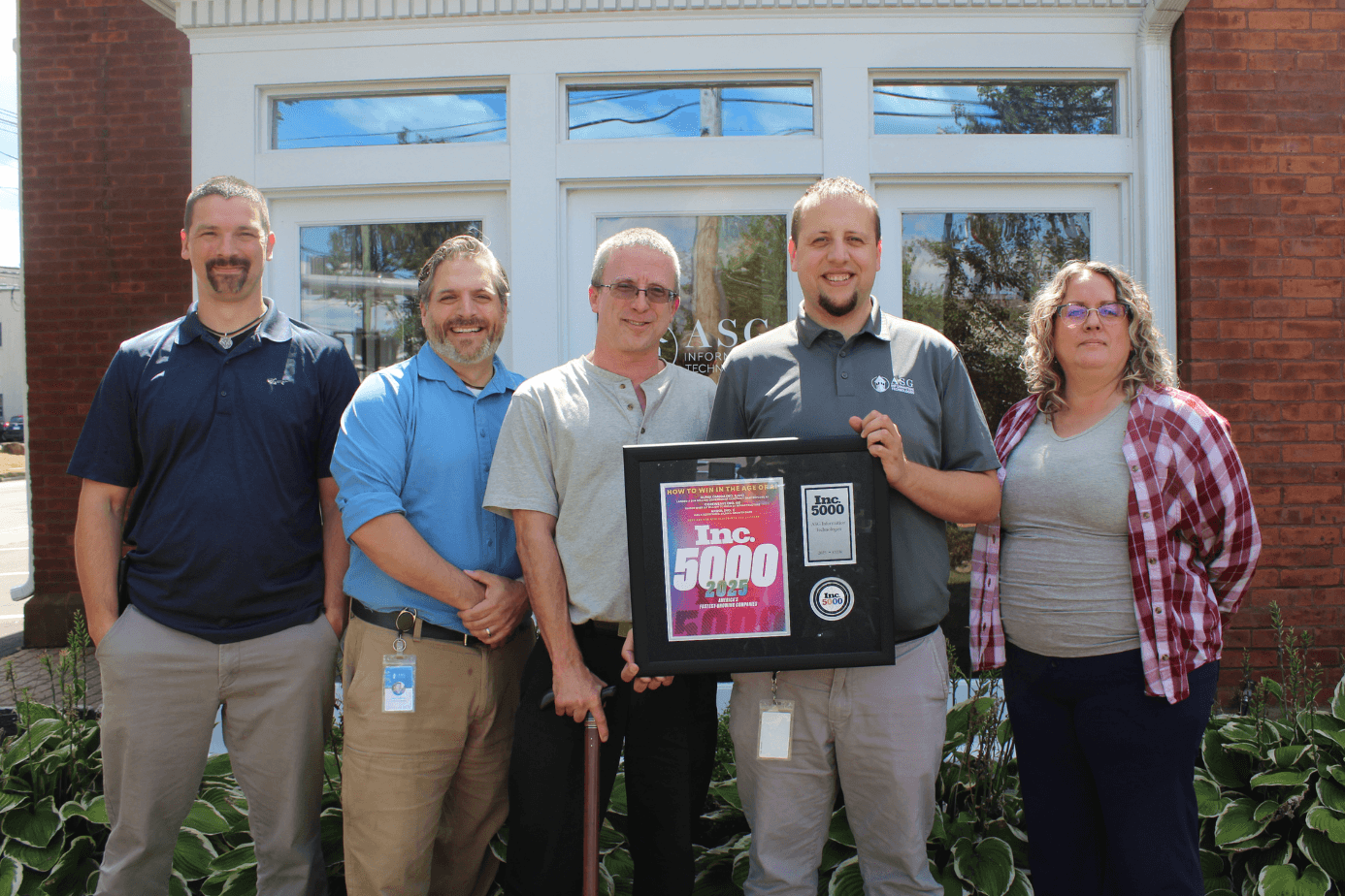 The ASG leadership team outside the Wallingford office holding the framed Inc. 5000 award