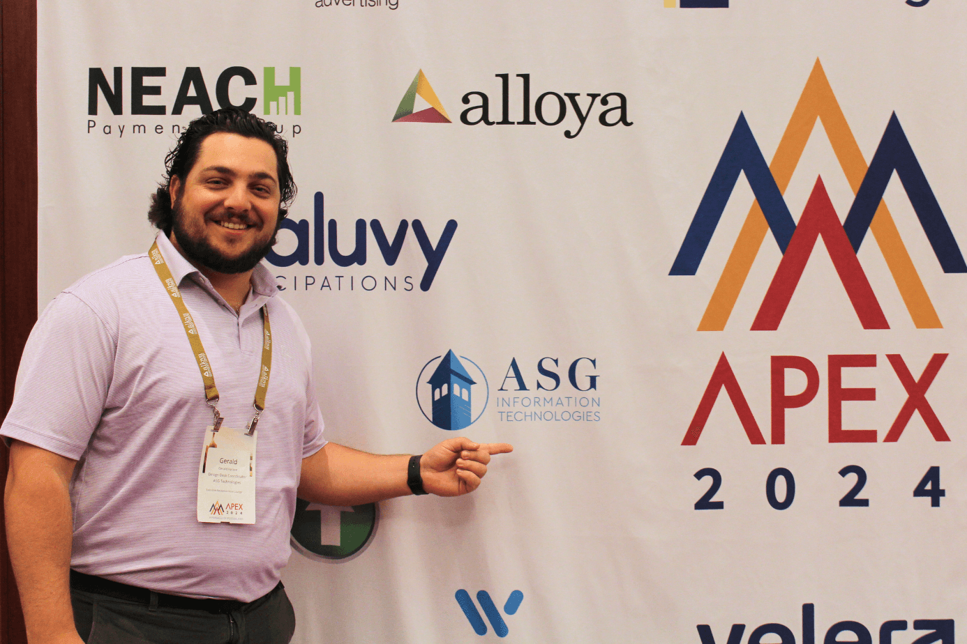 An ASG team member at the APEX 2024 conference beside the ASG Information Technologies sponsor banner