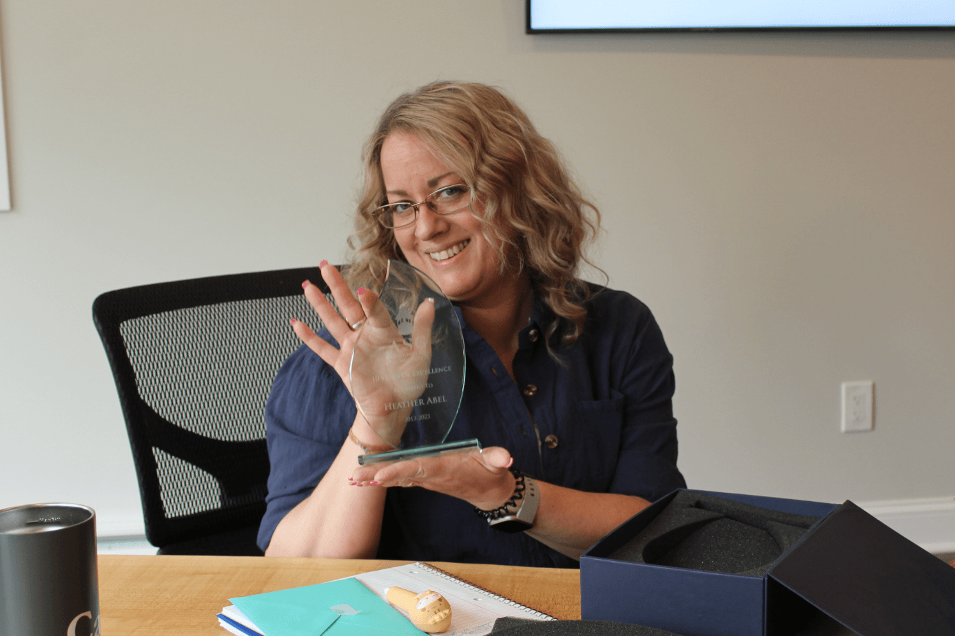 An ASG team member smiling as she holds her 10-year Years of Service Excellence glass award